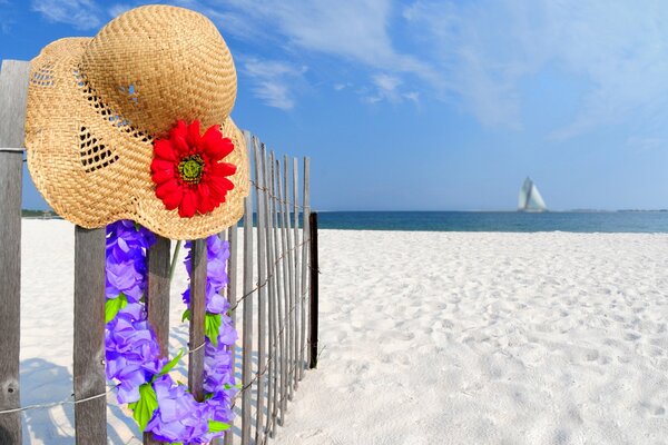 Hat with red color and beads of purple flowers on the fence