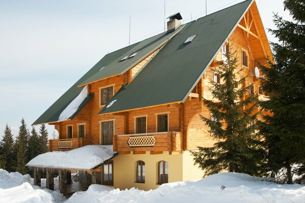 Two-storey cottage in a snow blanket among fir trees