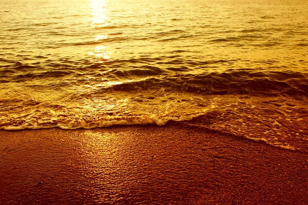 Küste bei Sonnenuntergang. Wellen im Sand