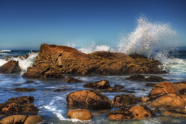 Salpicaduras de las olas contra las rocas en el mar