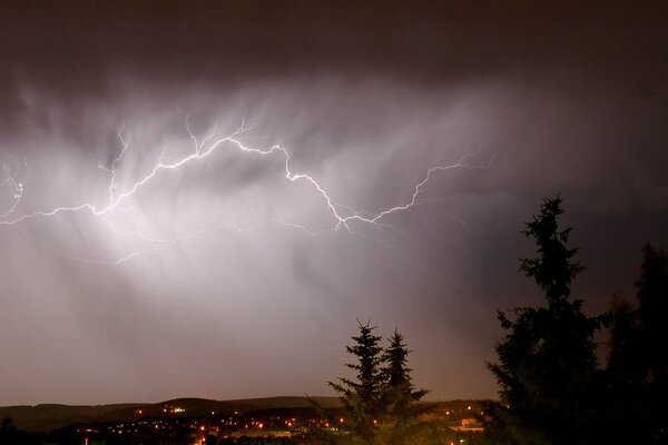 Lightning cuts through a thick veil of brown clouds over the night city