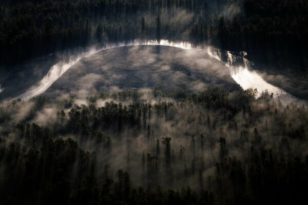 La nebbia si diffonde sul fiume e sulla fitta foresta