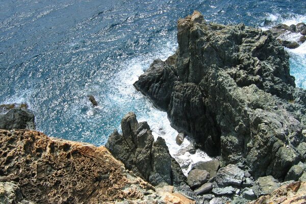 Das Meer mit blaugrünem Wasser wird von steilen Klippen umspült