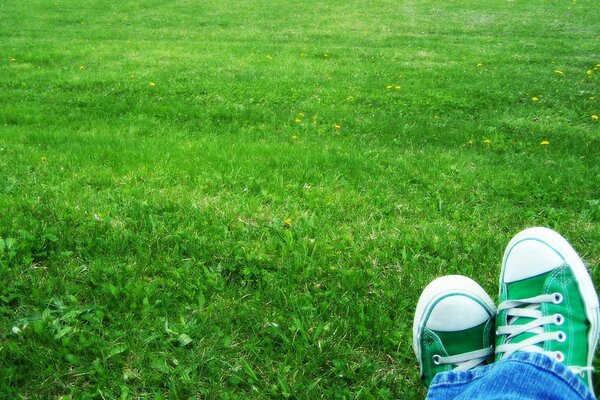 Zdjęcie stóp w jasnych tenisówkach na trawniku