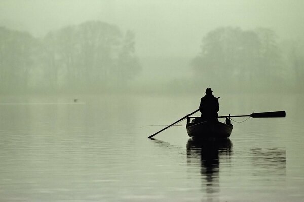 Pescatore solitario su una barca nella nebbia