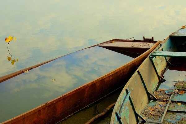 Los barcos rotos en el muelle reflejan las nubes