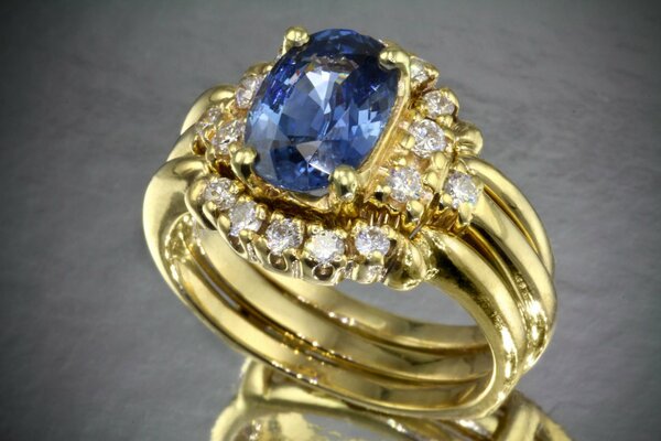 Złoty pierścionek z dużym niebieskim kamieniem i rozproszonymi diamentami