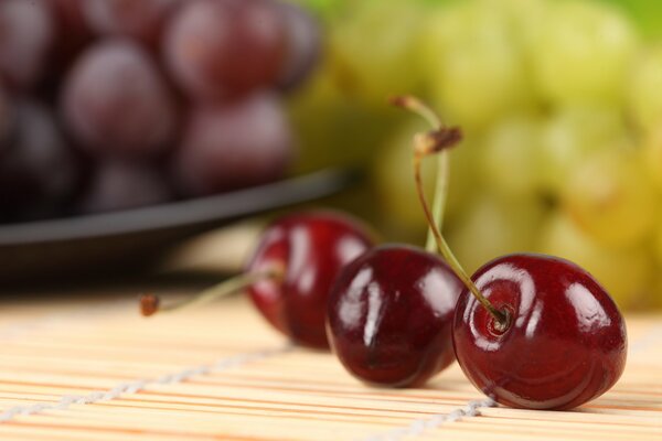 Ripe cherries on the background of grapes