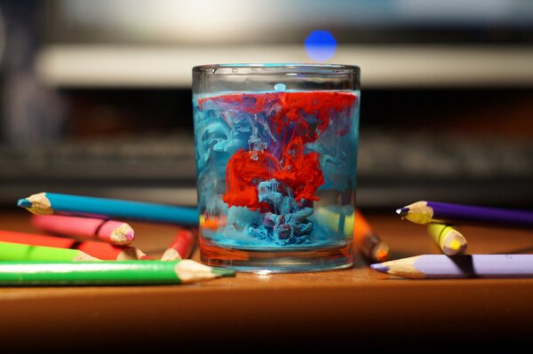 Eau pittoresque dans un verre et des crayons de couleur