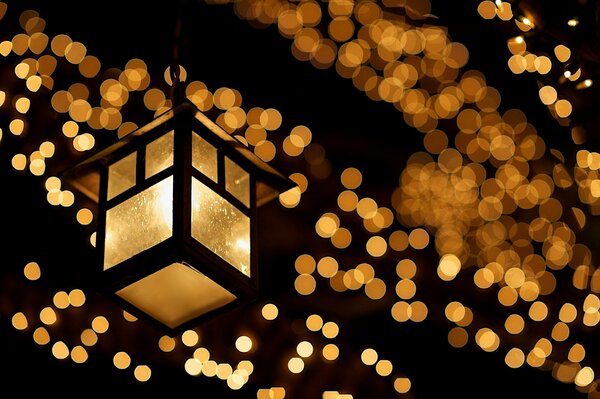 Night shot of a burning lantern and a garland of yellow lights