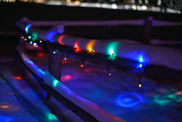 Wooden fence with colorful garland at night