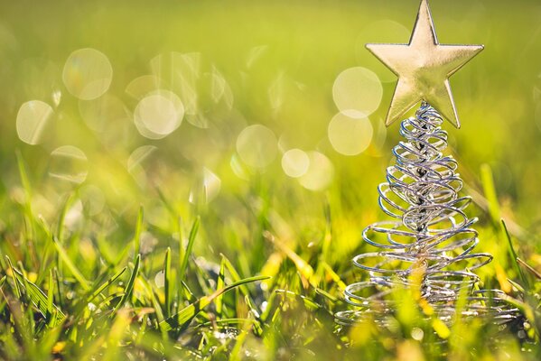 A toy Christmas tree stands in the grass