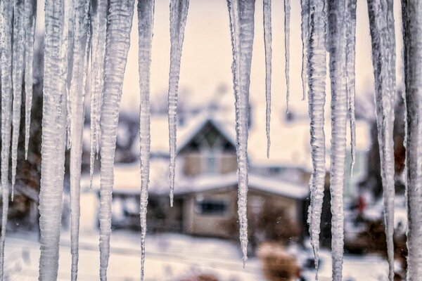 Eiszapfen auf dem Hintergrund der Dorfhäuser