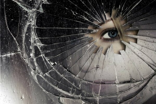 The girl looks through the hole of the broken mirror