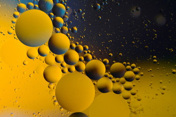 On the water, oil drops of different sizes on a yellow-blue background