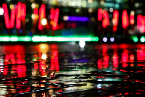 The delight of bright red neon signs on wet asphalt at night after rain