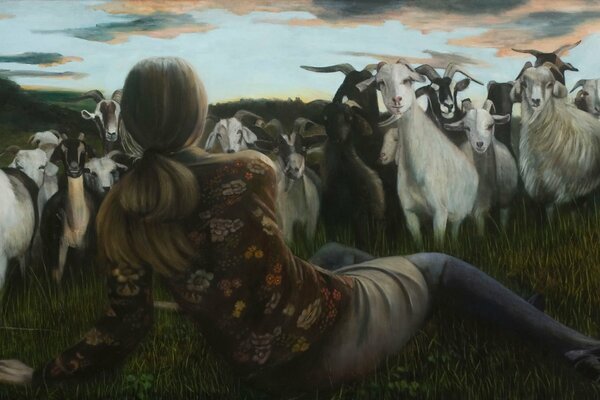 A girl lying in a meadow and sheep grazing in a meadow are looking at each other