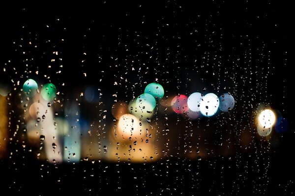 Światła miasta przez krople deszczu na szkle