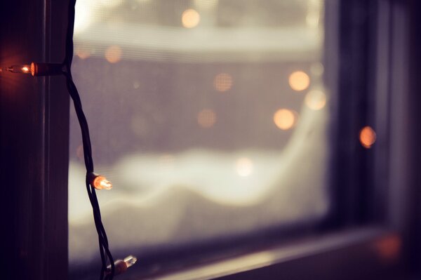 Śnieg na oknie i światła girlandy