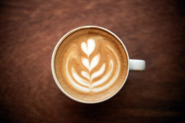 Tazza di caffè cappuccino con schiuma e motivo a fiori con cuore