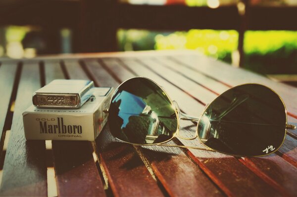 Ray ban aviators and a pack of marlboros with a zippo lighter