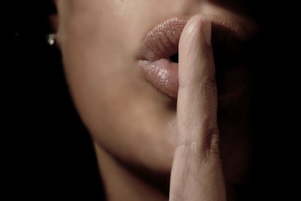 The girl shows a sign of silence by raising her finger to her lips