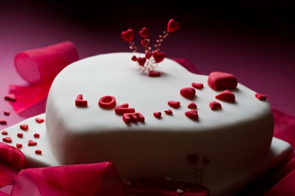Pastel en forma de corazón cubierto con masilla blanca con letras de amor