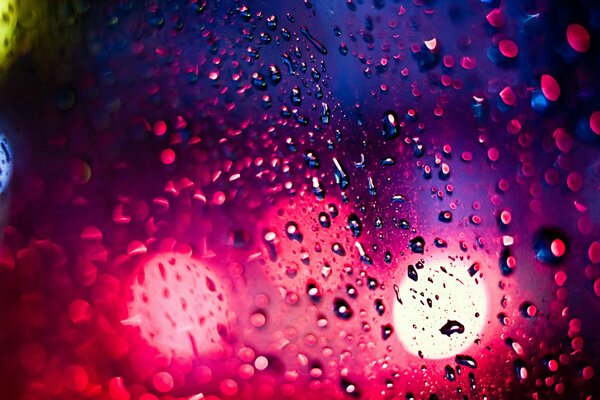 Gocce di pioggia sul vetro della città di notte