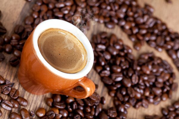 Tasse heißen Kaffee auf dem Hintergrund eines Herzens aus Kaffeebohnen