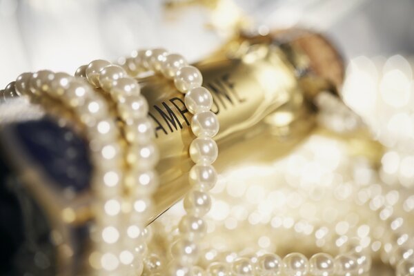 Perłowe koraliki owinięte wokół butelki szampana