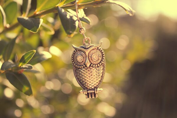 A pendant in the form of an owl hangs on a branch