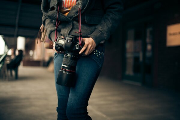 Девушка в руках с фотоаппаратом canon