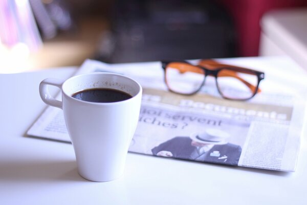 Kaffeetasse mit Brille und Zeitung auf dem Tisch