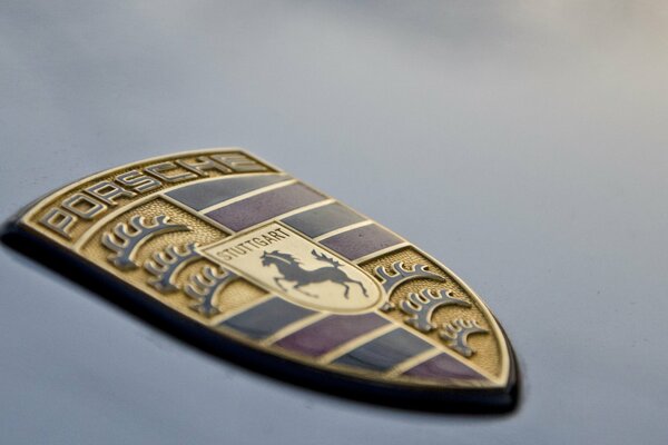 Schild mit Pferd. Porsche-Logo auf der Motorhaube