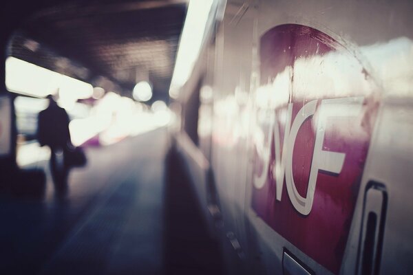 A man with a briefcase next to a subway train in a blurry image go away