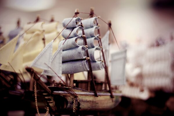 Model of a wooden boat with masts and sails on a blurry background