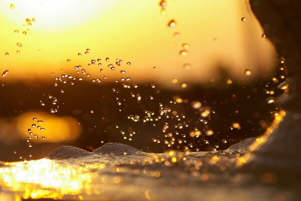 Spruzzi di acqua di mare sullo sfondo di un tramonto sfocato