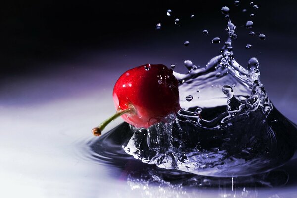 Salpicaduras de agua de la caída de una baya de cereza