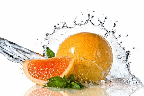 Water splashes on a grapefruit with mint