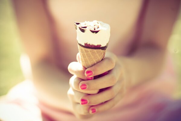 A girl with a bright manicure holds an ice cream