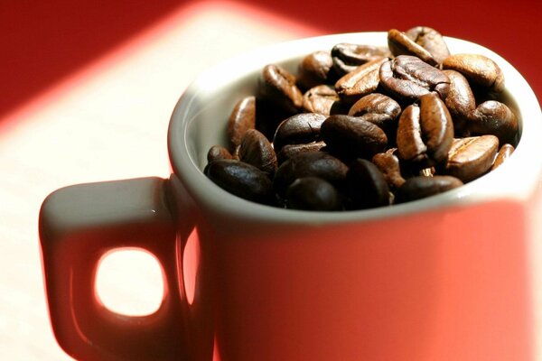 Taza roja llena de granos de café