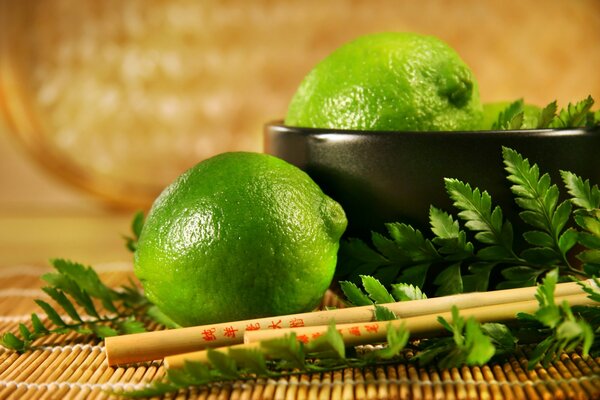 Lime et légumes verts avec des baguettes chinoises dans un bol