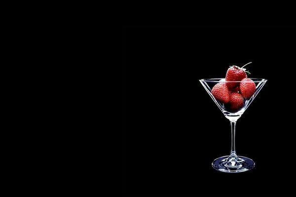 Transparent glass with strawberries on a black background