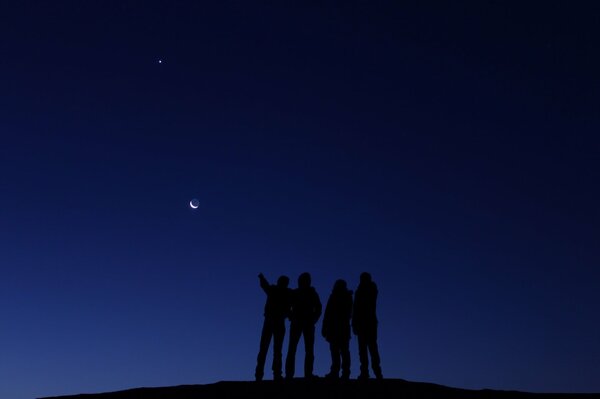 Silhouettes of people looking at the moon