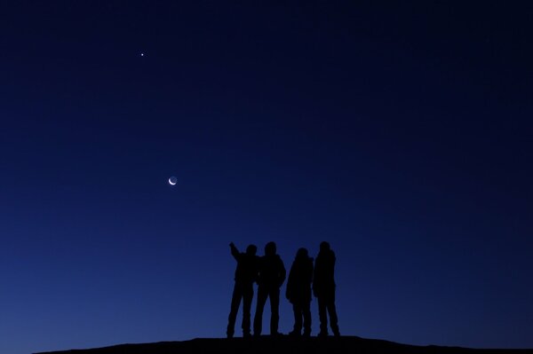Silhouettes de personnes regardant la lune