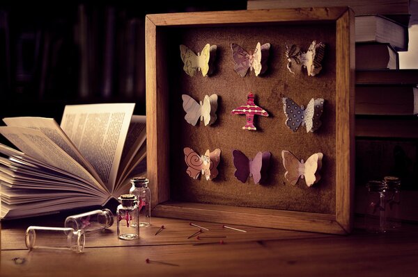 Marco con mariposas en la mesa entre libros, agujas y burbujas