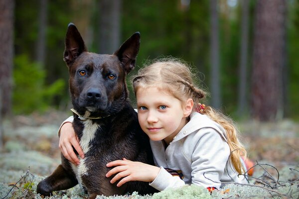 Fille dans une étreinte avec un chien dans la forêt