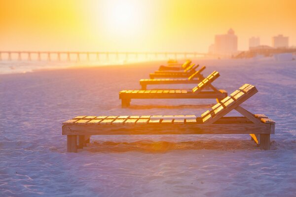 Sunrise. a row of deck chairs on a sand terminal against a brick wall