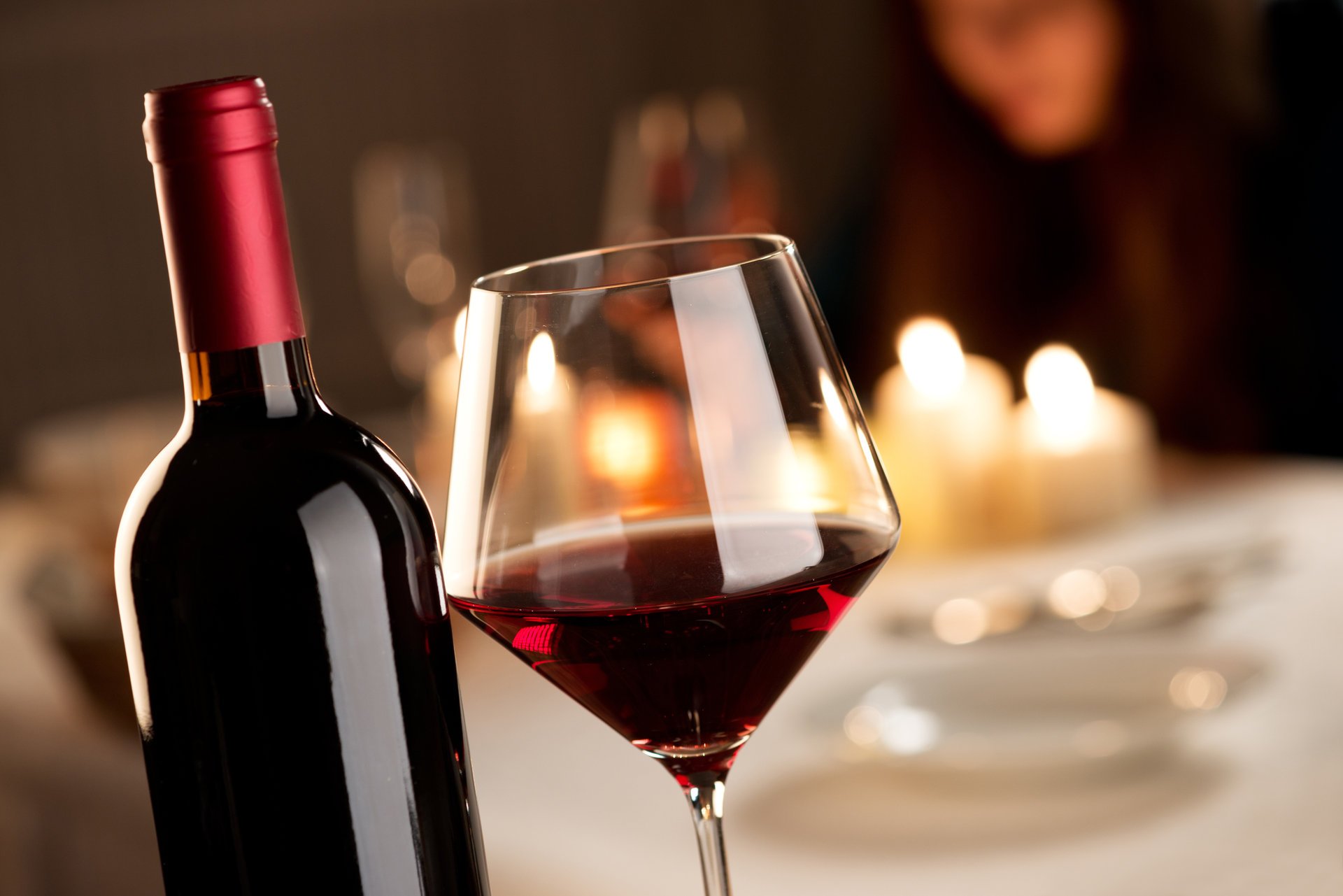vino rosso bicchiere bottiglia tavolo candele bokeh