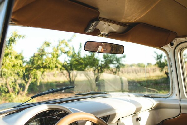 Oldtimer mit Blick auf die Landschaft und der Reflexion des Paares im Spiegel
